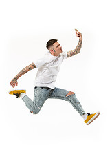 Image showing Full length of handsome young man taking selfie while jumping