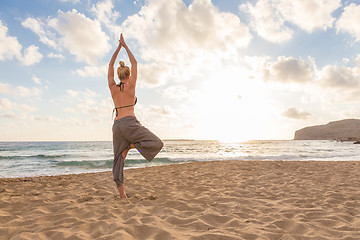 Image showing Woman practicing yoga on sea beach at sunset.