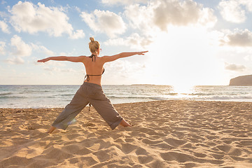 Image showing Woman practicing yoga on sea beach at sunset.