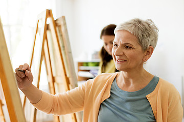 Image showing senior woman drawing on easel at art school studio