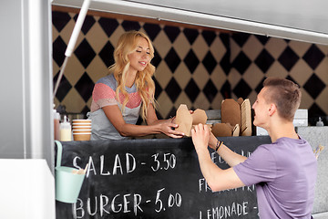 Image showing saleswoman at food truck serving male customer