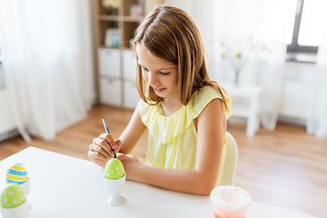 Image showing happy girl coloring easter eggs at home