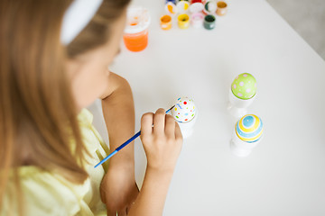 Image showing close up of girl coloring easter egg by paintbrush