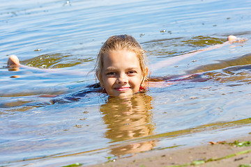 Image showing A ten-year-old girl lies in the water near the river