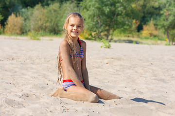 Image showing Teen girl sits on a river sandy river beach