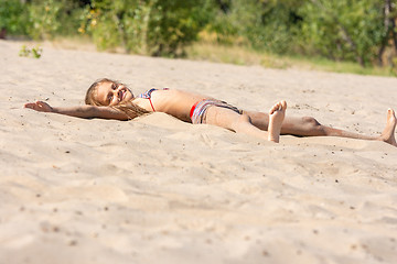 Image showing Teen girl sunbathes alone on a river sandy river beach