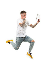 Image showing Image of young man over white background using laptop computer while jumping.