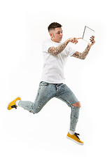 Image showing Image of young man over white background using laptop computer while jumping.