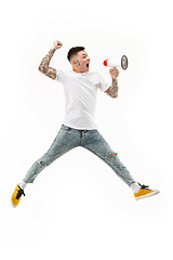 Image showing Jumping fan on white background. The young man as soccer football fan with megaphone