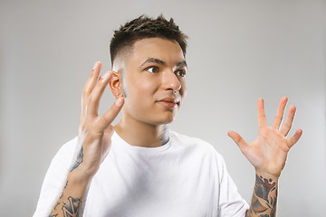 Image showing The young attractive man looking suprised isolated on gray