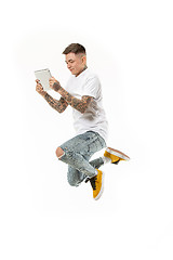 Image showing Image of young man over white background using laptop computer while jumping.