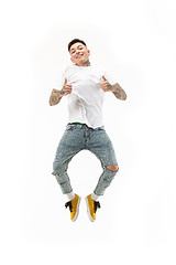 Image showing Image of young man over white background using laptop computer while jumping.