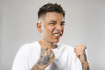 Image showing The young emotional angry man screaming on gray studio background