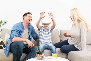 Image showing Happy family at home on living room sofa having fun playing games using virtual reality headset