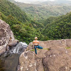 Image showing Active sporty woman relaxing in nature, practicing yoga on high clif by 500 feet waterfall at Black river gorges national park on tropical paradise island of Mauritius