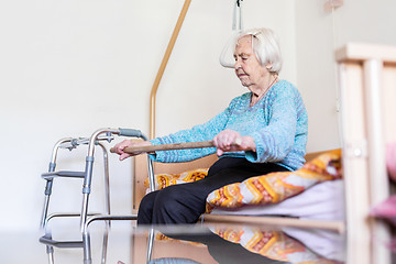 Image showing Elderly 96 years old woman exercising with a stick sitting on her bad.