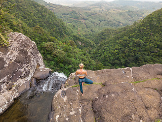 Image showing Active sporty woman relaxing in nature, practicing yoga on high clif by 500 feet waterfall at Black river gorges national park on tropical paradise island of Mauritius