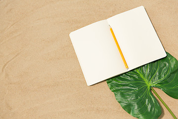 Image showing notebook with pencil and leaf on beach sand