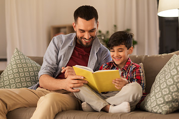 Image showing happy father and son reading book sofa at home