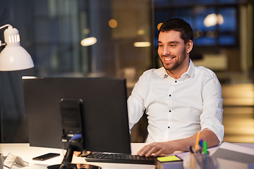 Image showing happy businessman with computer at night office