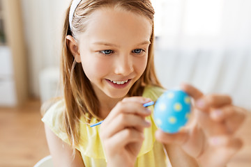 Image showing happy girl coloring easter egg at home