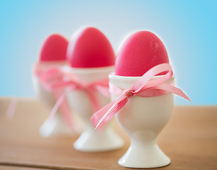 Image showing pink colored easter eggs in holders on table