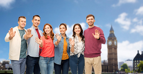 Image showing group of friends waving hands over london