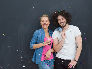 Image showing couple blowing confetti in the air isolated over gray