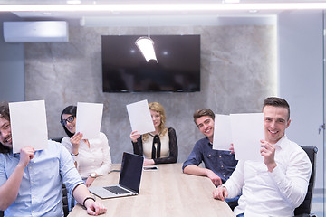 Image showing startup business team holding a white paper over face