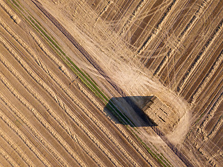 Image showing Top view from flying drones to an agricultural field after harvesting with a stacks of straw on it at summer day.