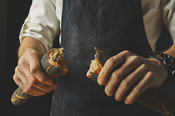 Image showing Hand breaks baguette