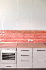 Image showing Kitchen facades with modern built-in kitchen appliances. Materials tiles in a trend color of the year 2019 Living Coral Pantone.