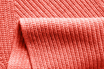 Image showing Warm wool knitted clothes background with fold in a trendy color of the year 2019 Living Coral Pantone.