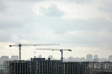 Image showing Building under construction with two tower cranes against a gray cloudy sky. Photo from the drone.