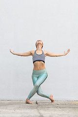 Image showing Fit sporty active girl in fashion sportswear doing yoga fitness exercise in front of gray wall, outdoor sports, urban style