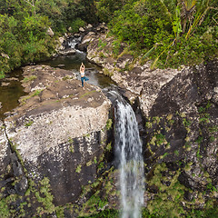 Image showing Active sporty woman relaxing in nature, practicing yoga on high clif by 500 feet waterfall at Black river gorges national park on tropical paradise island of Mauritius