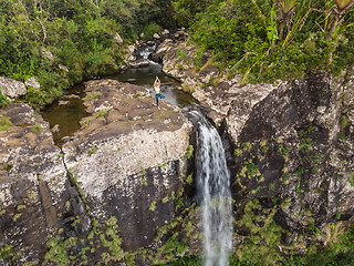 Image showing Active sporty woman relaxing in nature, practicing yoga on high clif by 500 feet waterfall at Black river gorges national park on tropical paradise island of Mauritius