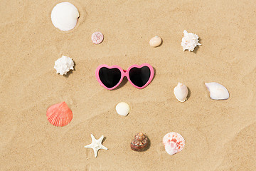 Image showing heart-shaped sunglasses and shells on beach sand