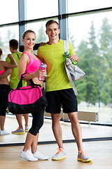 Image showing sportive couple with water bottles and bags in gym