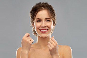 Image showing happy young woman with dental floss cleaning teeth