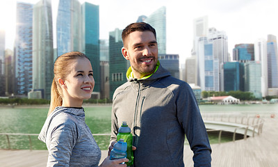 Image showing couple with bottles of water over singapore city