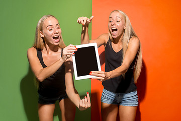 Image showing Portrait of a confident casual girls showing blank screen of laptop isolated over colorful background