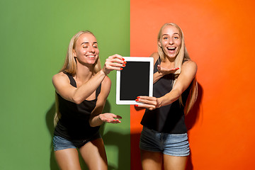 Image showing Portrait of a confident casual girls showing blank screen of laptop isolated over colorful background