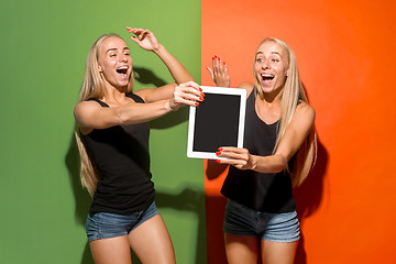 Image showing Portrait of a confident casual girls showing blank screen of laptop isolated over colorful background