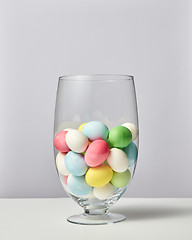 Image showing Glass vase with lots of small painted eggs on a gray background with copy space. Easter card layout