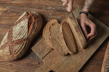 Image showing Women\'s hands cut organic bread