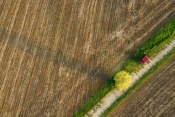 Image showing Aerial view from the drone, a bird\'s eye view of agricultural fields with a road through and red car on it in the spring evening at sunset