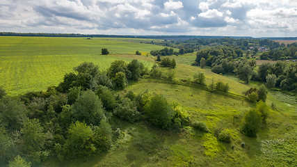 Image showing Summer rural landscape with green fields, meadows, forests against cloudy background. Aerial view from drone.