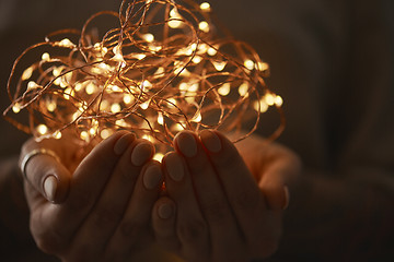 Image showing bright christmas lights in woman\'s hands