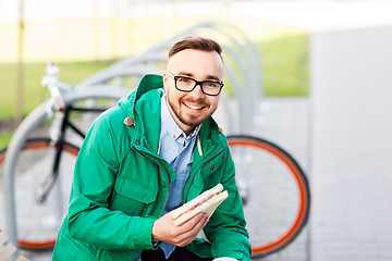 Image showing happy young man or hipster with sandwich outdoors